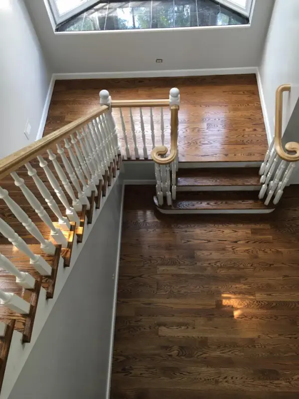 Grand staircase refinishing with wide landing – Lake Forest | FLOORecki Floors & Stairs Grand staircase with a wide landing and massive posts refinished in a Lake Forest home