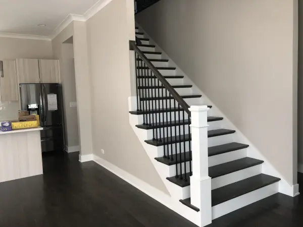 Dark stained staircase with white square posts – FLOORecki Floors & Stairs Dark brown stained staircase with white square posts, stained square handrails, and black iron spindles in a Chicago home