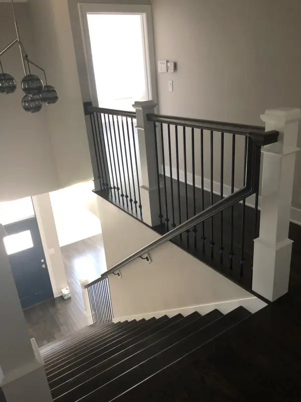 Dark stained stairs with white square posts – FLOORecki Floors & Stairs Dark brown stained stairs with white square posts, stained square handrails, and black iron spindles in a Chicago home