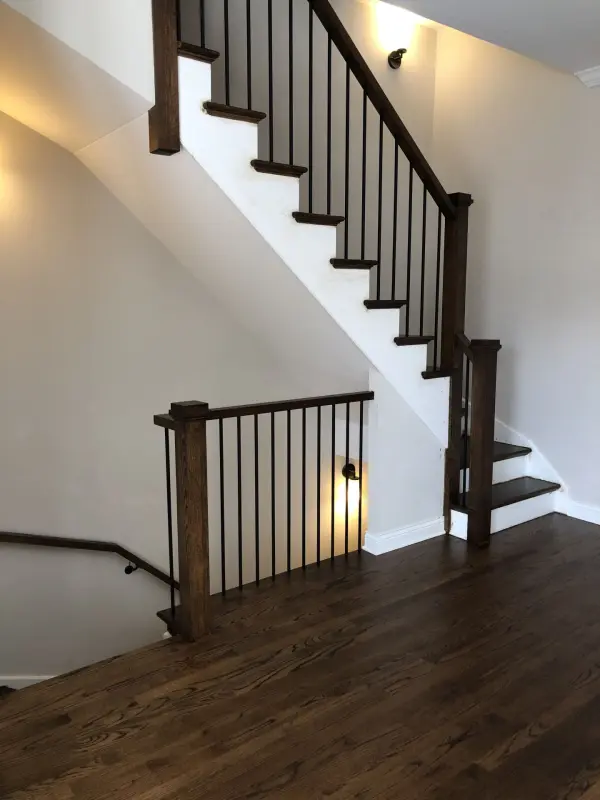 Red oak floors and brown-stained stairs – Chicago townhouse | FLOORecki Stained red oak hardwood floors with brown stained stairs and black iron spindles in a Chicago townhouse