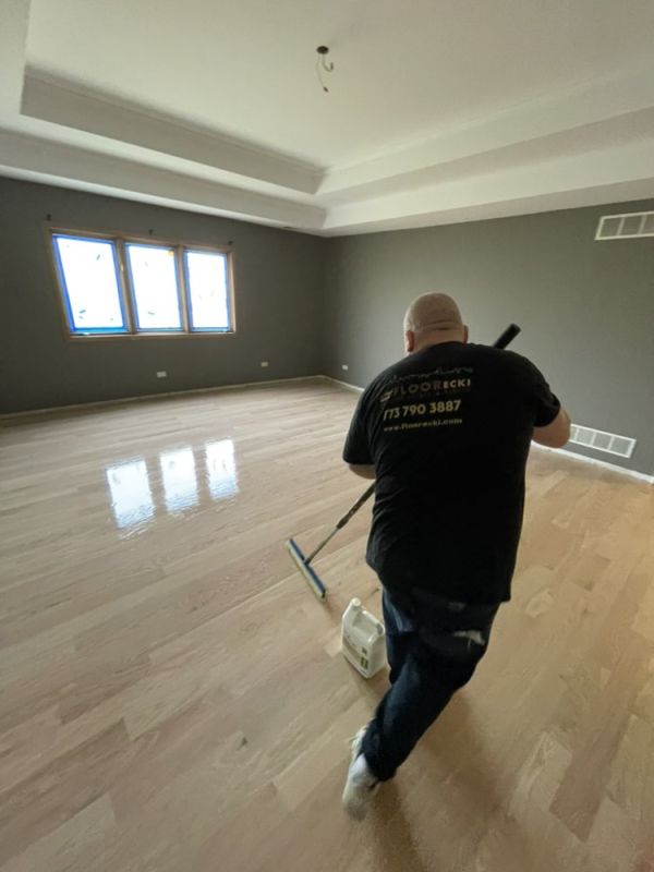 FLOORecki technician applying a finish coat during hardwood floor refinishing in a Chicago home 