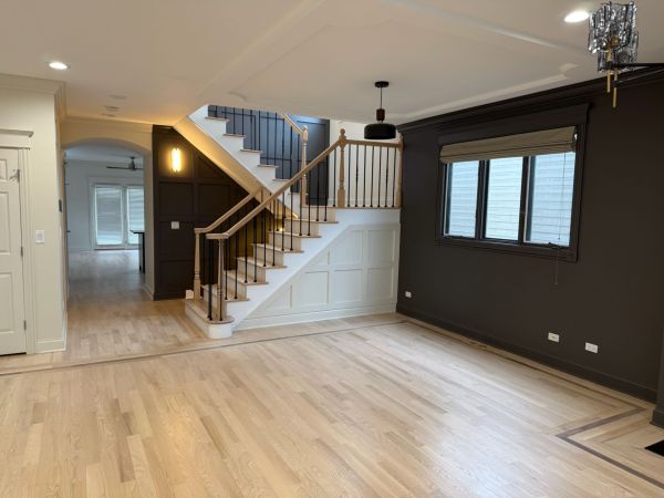 White oak hardwood floors with a refinished staircase, square posts, and black iron spindles in a Chicago home 