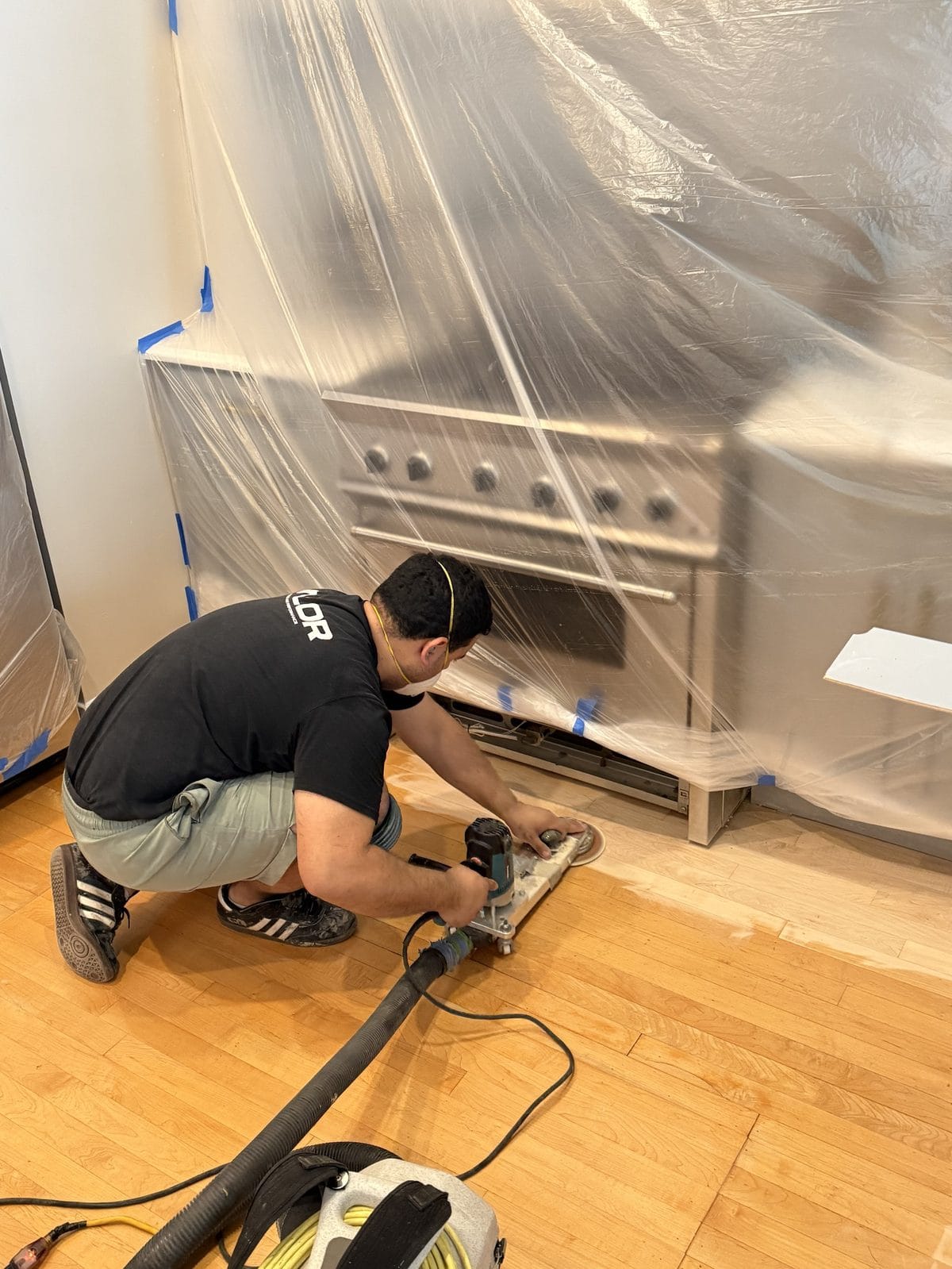 FLOORecki craftsman edge-sanding a hardwood floor with dust-containment vacuum in a Chicago kitchen