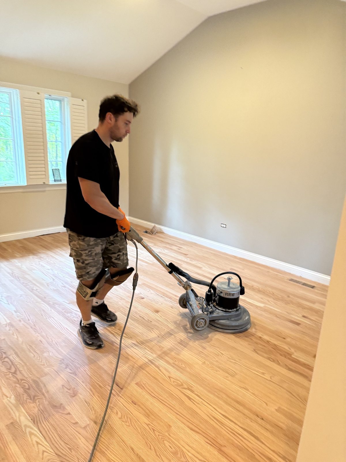 Krzysztof 'Chris', FLOORecki co-owner, buffing a freshly sanded red oak floor during refinishing in a Chicago home