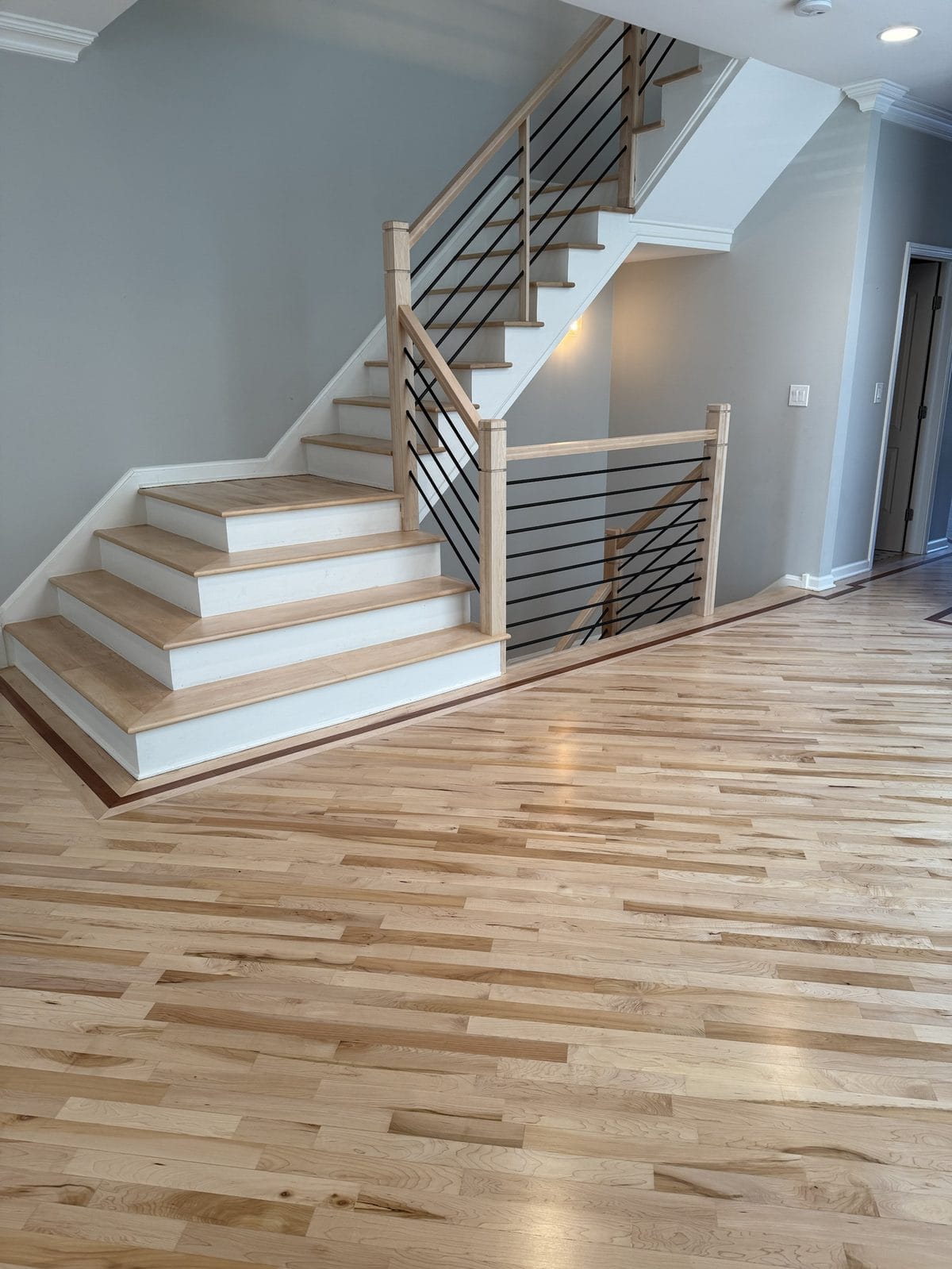 Refinished natural-tone hardwood floor and staircase with updated railing in Chicago