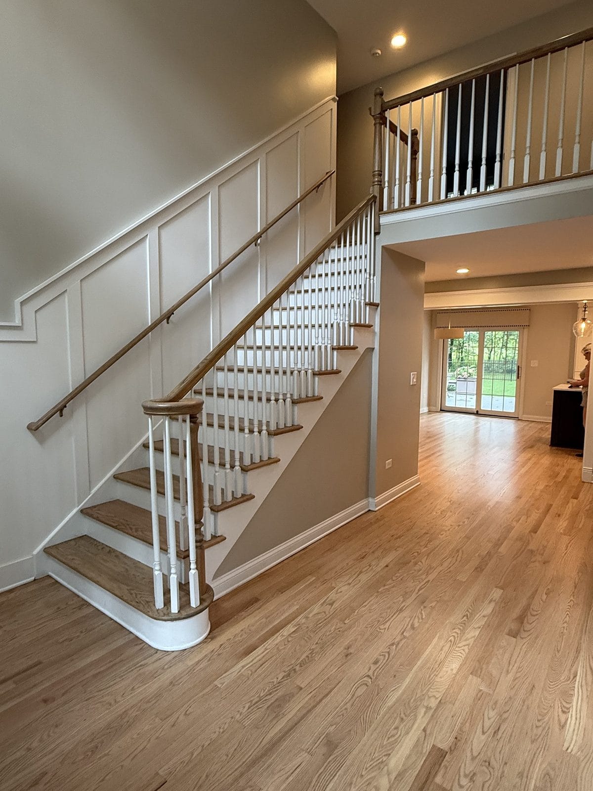 Refinished light natural red oak floors and staircase in a bright two-story foyer, Chicago suburb